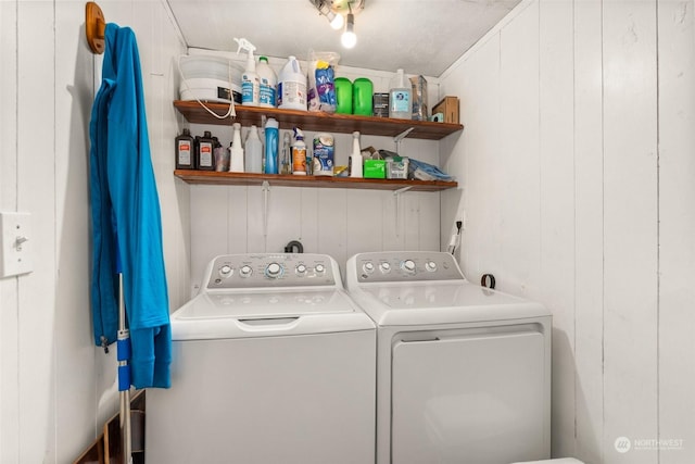 clothes washing area with washing machine and dryer and wooden walls