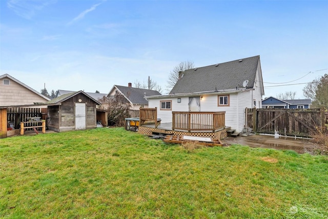 back of property with a deck, a storage unit, and a lawn