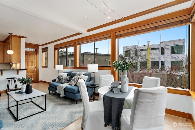 interior space featuring ornamental molding, beamed ceiling, and light wood-type flooring