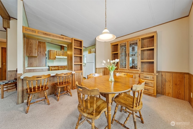 carpeted dining area with crown molding and wood walls