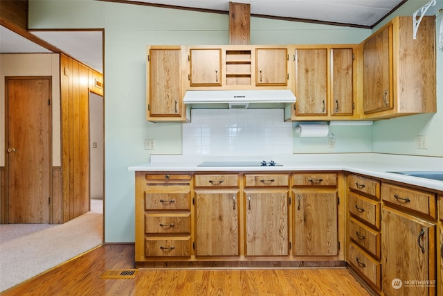 kitchen with black electric stovetop, vaulted ceiling, ornamental molding, and light wood-type flooring