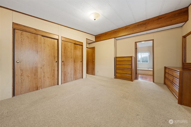 unfurnished bedroom featuring carpet floors, multiple closets, and ensuite bathroom