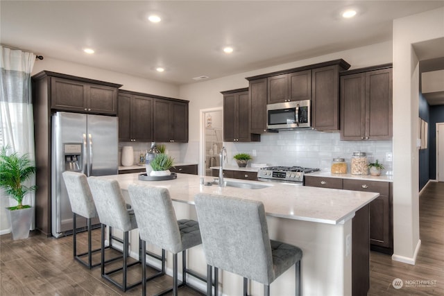 kitchen featuring sink, dark hardwood / wood-style flooring, an island with sink, and appliances with stainless steel finishes