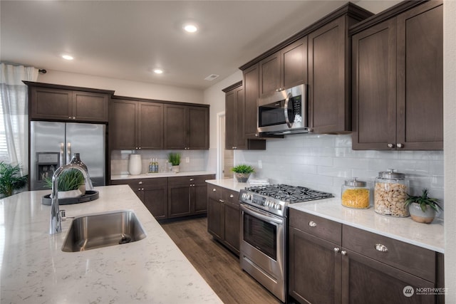 kitchen featuring light stone countertops, dark brown cabinets, stainless steel appliances, and sink