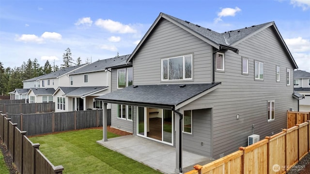 back of property with a patio area, a shingled roof, a lawn, and a fenced backyard