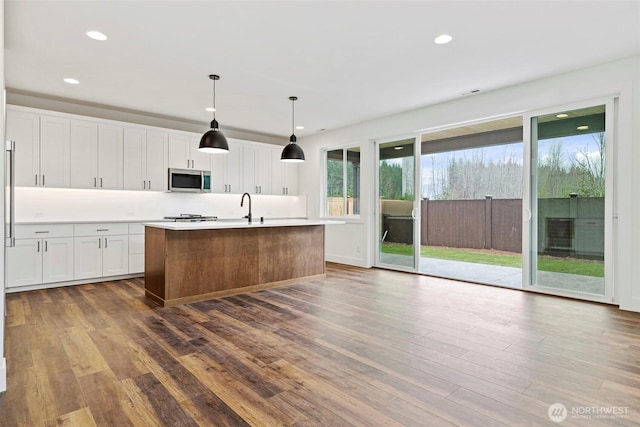 kitchen featuring white cabinetry, stainless steel microwave, and dark wood finished floors