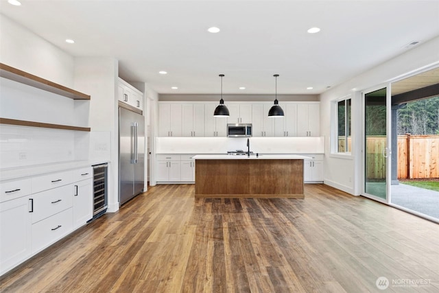 kitchen with appliances with stainless steel finishes, wood finished floors, beverage cooler, and open shelves