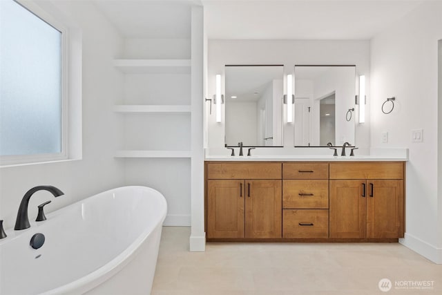 bathroom featuring double vanity, a freestanding tub, built in features, and a sink