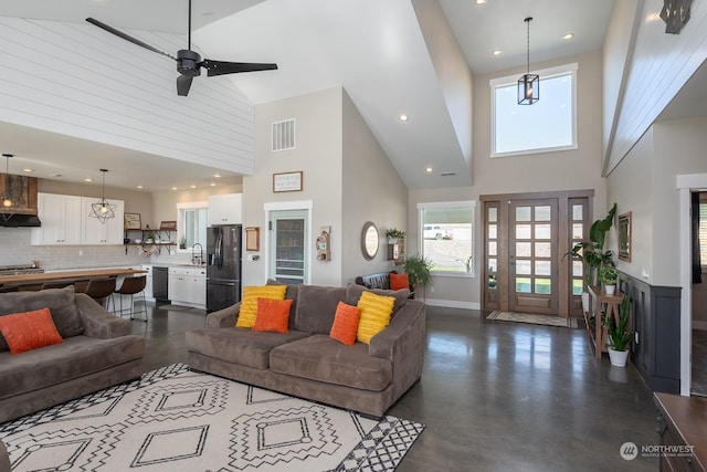 living room featuring ceiling fan, sink, high vaulted ceiling, and concrete flooring