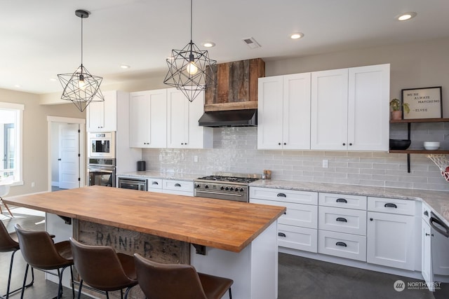 kitchen featuring white cabinetry, stainless steel appliances, wood counters, pendant lighting, and a kitchen island