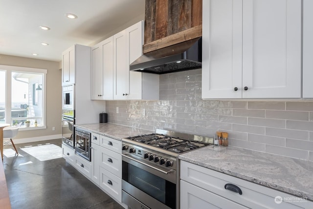 kitchen featuring white cabinets, decorative backsplash, wall chimney exhaust hood, appliances with stainless steel finishes, and light stone counters