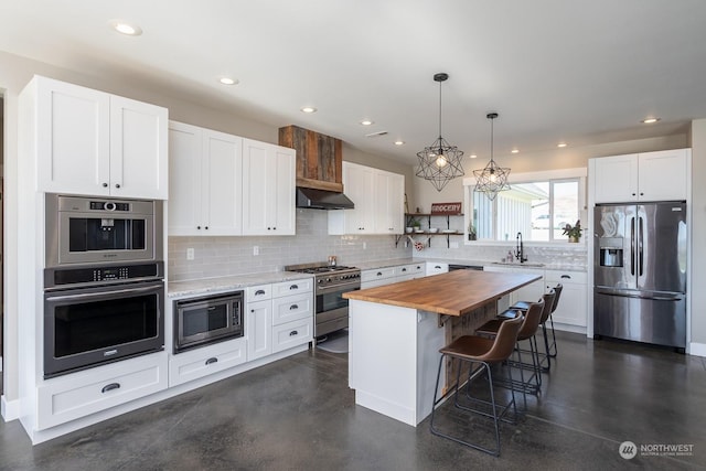 kitchen featuring white cabinets, stainless steel appliances, a kitchen island, and butcher block countertops