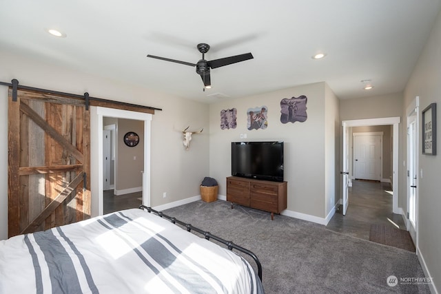 bedroom featuring a barn door, ceiling fan, and dark carpet