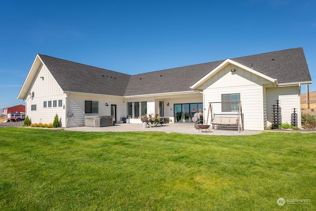 rear view of house with a hot tub, a patio area, and a lawn