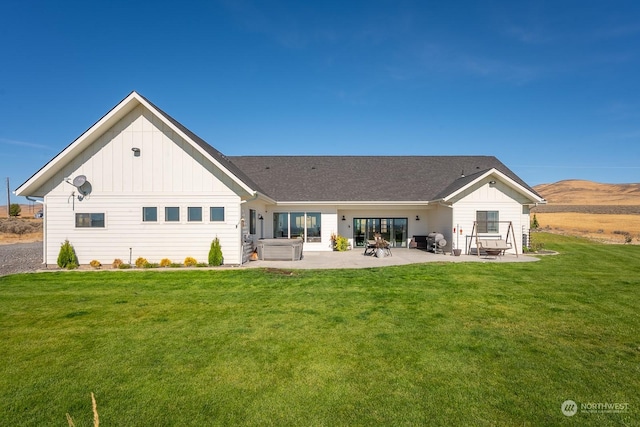 rear view of house with a lawn, a patio area, and a hot tub