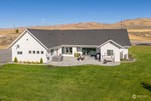 back of property featuring a mountain view, a patio area, and a lawn