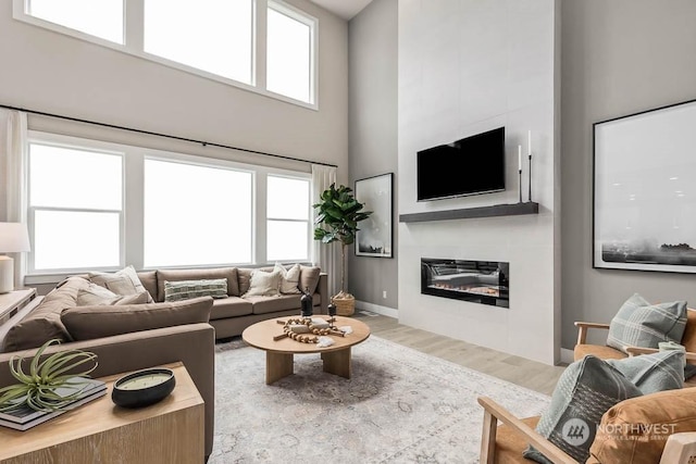 living room with a towering ceiling, hardwood / wood-style flooring, and plenty of natural light