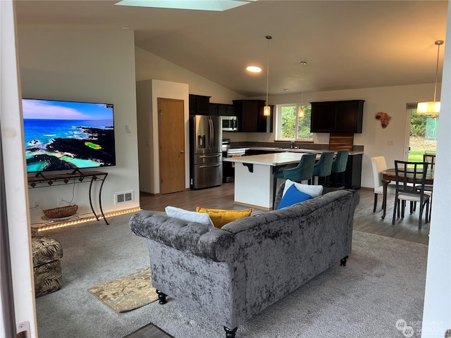 carpeted living room featuring lofted ceiling and sink