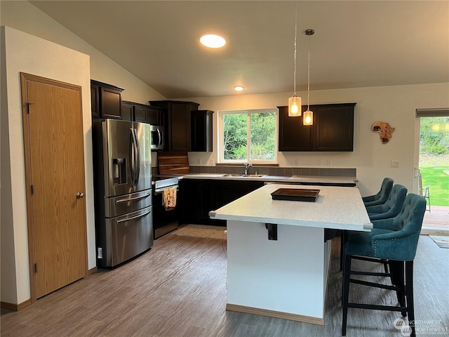 kitchen with a center island, hanging light fixtures, lofted ceiling, a breakfast bar area, and appliances with stainless steel finishes