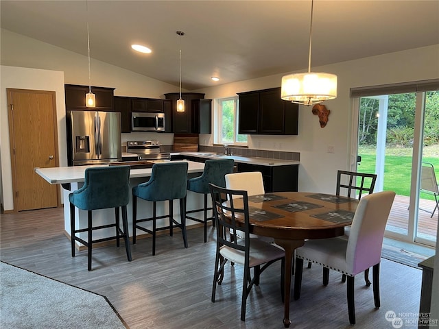 dining space with hardwood / wood-style flooring, vaulted ceiling, and sink