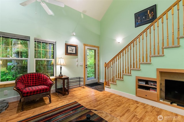 interior space featuring stairway, wood finished floors, baseboards, and high vaulted ceiling