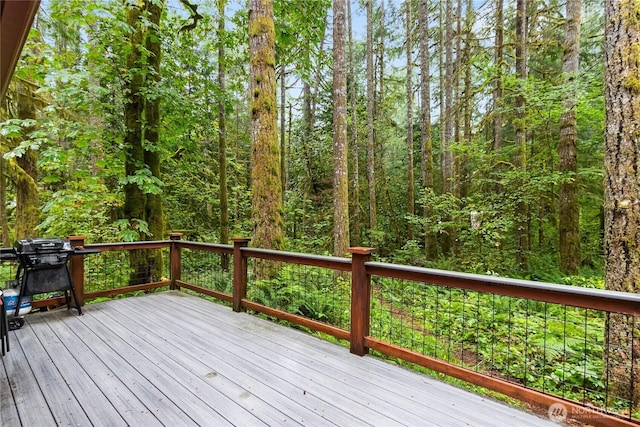 wooden terrace featuring a wooded view and grilling area