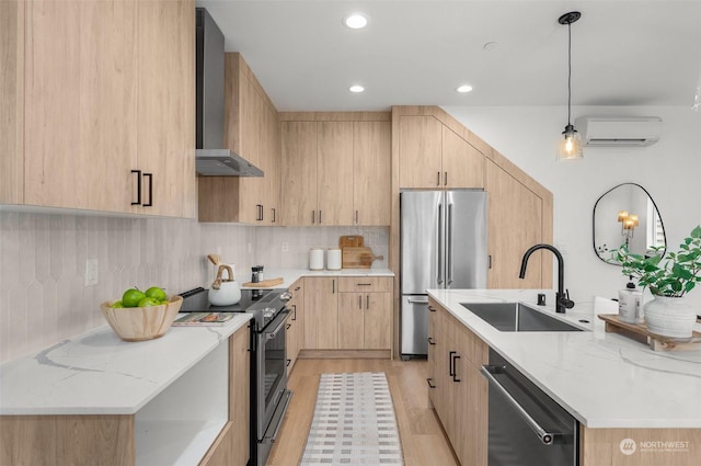 kitchen featuring pendant lighting, wall chimney range hood, stainless steel appliances, light brown cabinetry, and sink