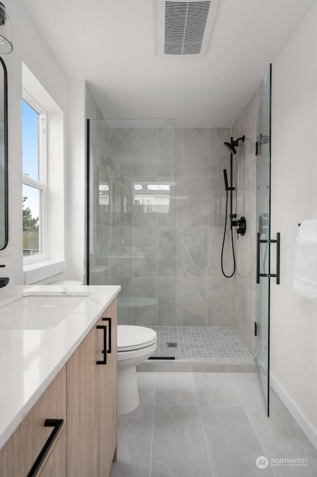 bathroom with toilet, tile patterned flooring, walk in shower, and vanity