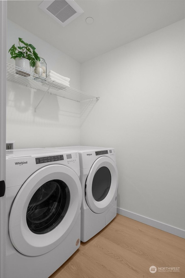 washroom with washer and clothes dryer and light hardwood / wood-style flooring