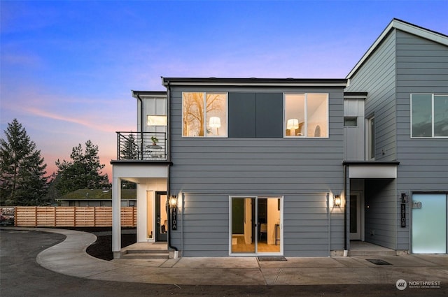 back house at dusk featuring a balcony