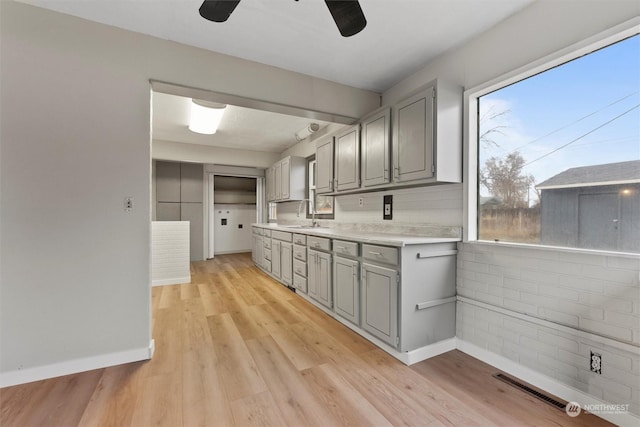 kitchen with light hardwood / wood-style floors, a wealth of natural light, gray cabinetry, and sink