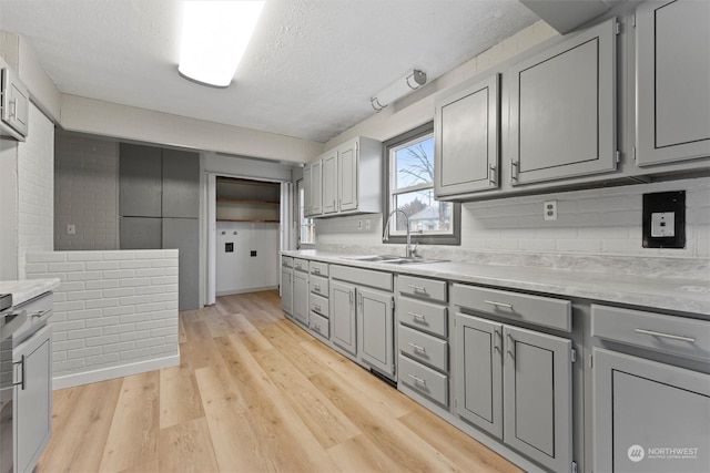 kitchen featuring a textured ceiling, gray cabinets, sink, and light hardwood / wood-style flooring