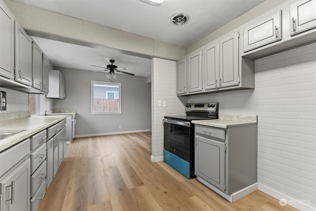 kitchen featuring gray cabinets, ceiling fan, light hardwood / wood-style flooring, and stainless steel range with electric stovetop