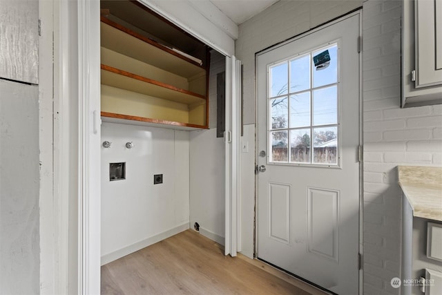 clothes washing area with hookup for an electric dryer, light hardwood / wood-style floors, brick wall, and hookup for a washing machine