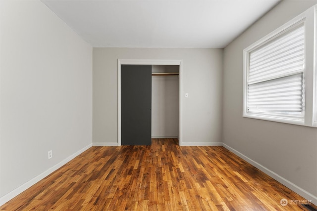 unfurnished bedroom with multiple windows, a closet, and dark hardwood / wood-style flooring