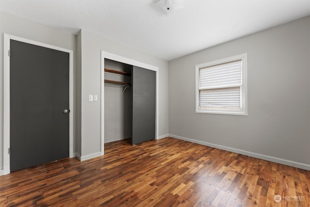 unfurnished bedroom with dark hardwood / wood-style flooring and a closet