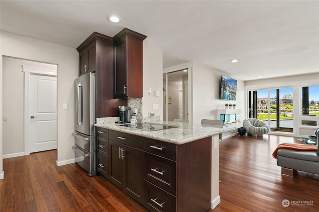 kitchen with dark hardwood / wood-style floors, light stone countertops, black electric cooktop, tasteful backsplash, and kitchen peninsula