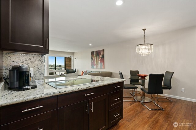 kitchen featuring hardwood / wood-style floors, hanging light fixtures, electric stovetop, light stone countertops, and a chandelier