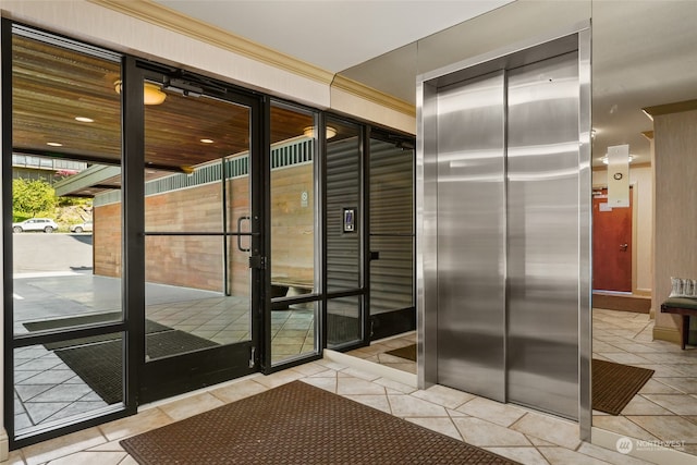 doorway with elevator, light tile patterned flooring, and ornamental molding