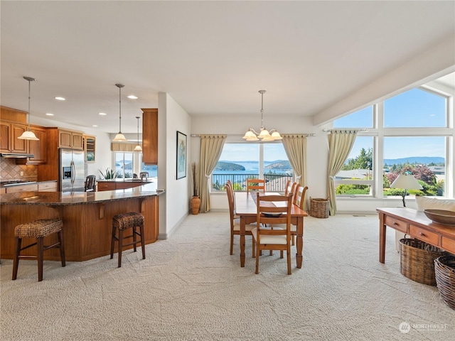 carpeted dining room with a water and mountain view and a chandelier