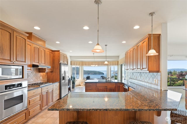 kitchen featuring dark stone counters, tasteful backsplash, decorative light fixtures, kitchen peninsula, and stainless steel appliances