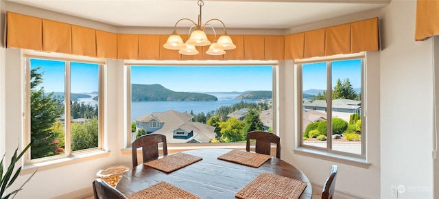 dining area featuring an inviting chandelier, a wealth of natural light, and a water and mountain view