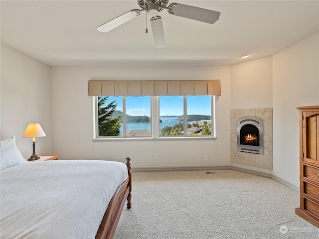 carpeted bedroom featuring a tile fireplace, ceiling fan, and a mountain view