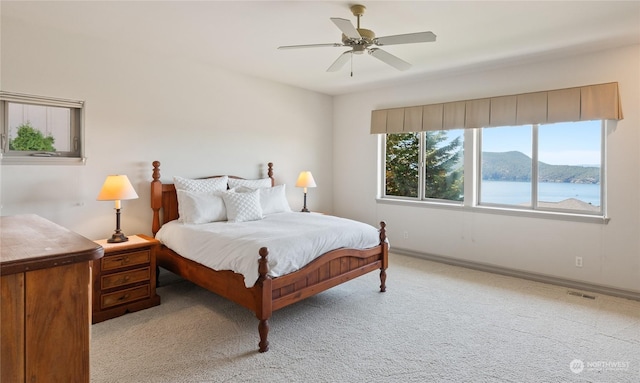 carpeted bedroom featuring ceiling fan and a water and mountain view