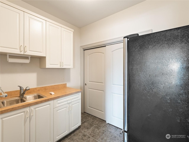 kitchen featuring white cabinetry, stainless steel fridge, and sink