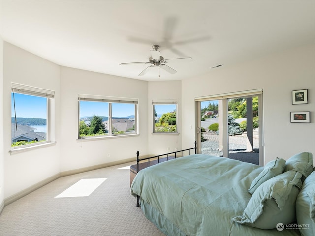 carpeted bedroom with access to exterior, multiple windows, and ceiling fan