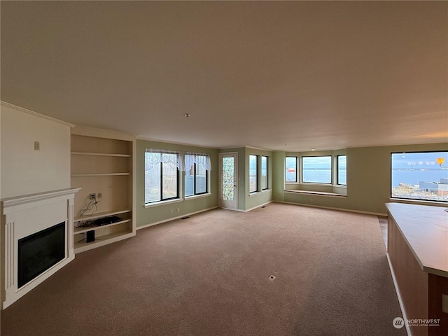 unfurnished living room featuring light colored carpet and built in features