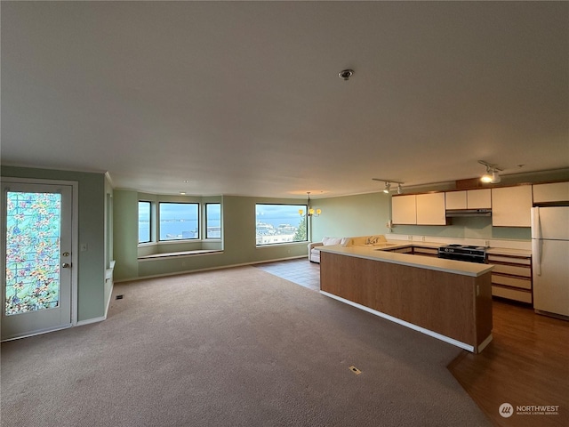 kitchen with light carpet, a chandelier, white cabinets, black gas range, and white fridge