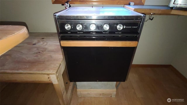 room details featuring hardwood / wood-style flooring and black / electric stove