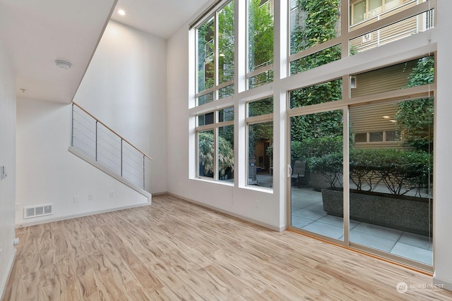 unfurnished living room featuring a high ceiling and light hardwood / wood-style flooring